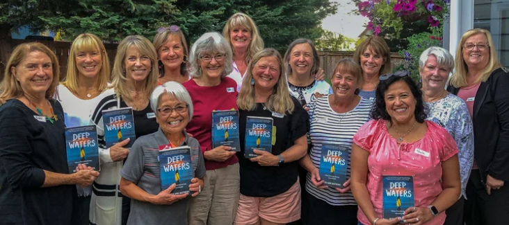 Readers gathering outdoors with copies of Deep Waters